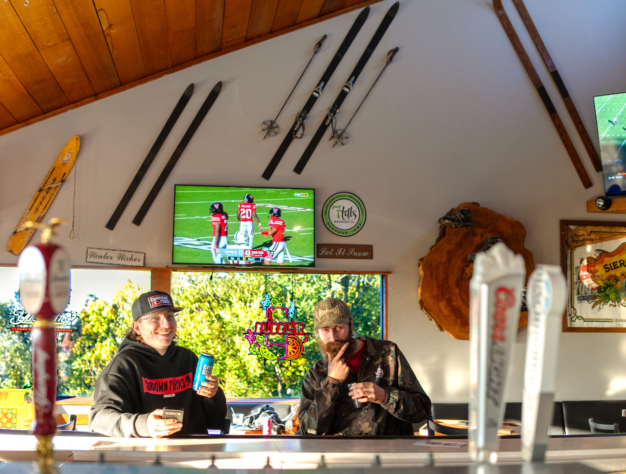 Two fans in Iowa gear watching football at the Tips Up bar